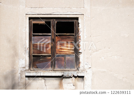 Old wooden window with broken glass on the wall of an abandoned house 122639311