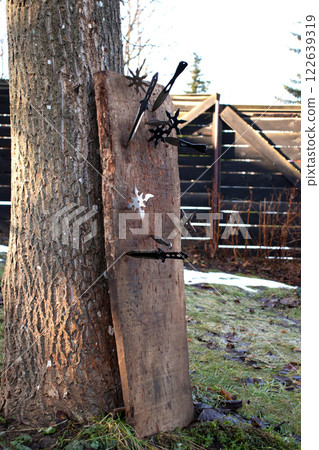 Close-up view of shurikens and knifes driven into a plank - selective focus Close-up view of shurikens and knifes driven into a plank - selective focus 122639319