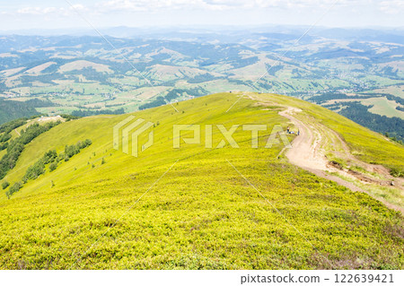 scenery with hiking path in summer. wonderful alpine meadow. beautiful mountain landscape with green hills and steep slopes. trail through borzhava ridge. view in to the valley. travel season scenery with hiking path in summer. wonderful alpine meadow. beautiful mountain landscape with green hills and steep slopes. trail through borzhava ridge. view in to the valley. travel season 122639421