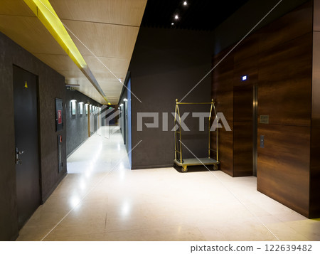 Interior of stylish hotel next to reception. Corridor of expensive hotel with elevator for staff and luggage cart to assist clients during check in. Delivery of luggage to your hotel room on trolley Interior of stylish hotel next to reception. Corridor of expensive hotel with elevator for staff and luggage cart to assist clients during check in. Delivery of luggage to your hotel room on trolley 122639482