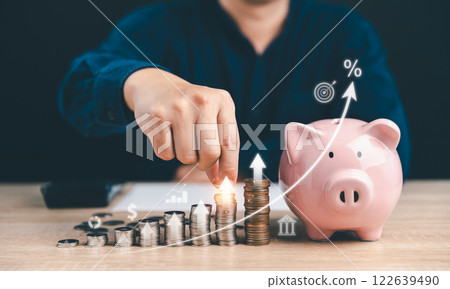 Man putting coins stacking with increasing graph for increase financial interest rate and business investment growth from dividend, Investor setup business objective target. 122639490