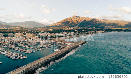 Aerial view of Puerto Banus marina with yachts, coastline, and the Sierra Blanca mountains in the Aerial view of Puerto Banus marina with yachts, coastline, and the Sierra Blanca mountains in the 122639891