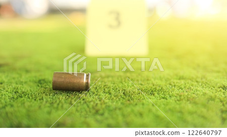 A spent bullet casing in focus, with a blurred forensic number 3 tag behind it, symbolizes crime scene investigation, evidence collection, and law enforcement efforts in forensic science. 122640797