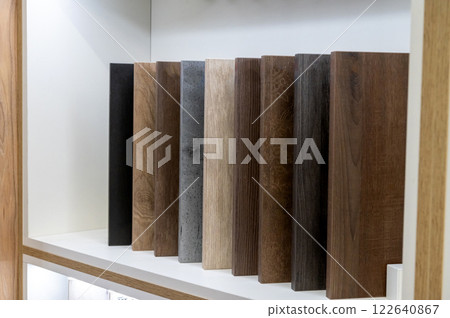 Wooden plank samples in various shades arranged on a shelf for interior design. 122640867
