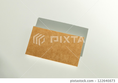 Blank brown cardboard lying on smooth white surface with shadow Blank brown cardboard lying on smooth white surface with shadow 122640873