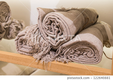 Rolled Beige Textured Throws on Wooden Shelf 122640881