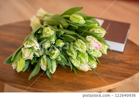 Unopened tulip bouquet on wooden table next to book. Unopened tulip bouquet on wooden table next to book. 122640936