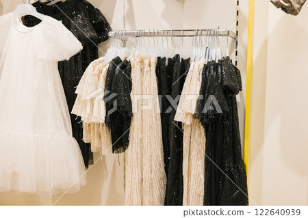 Elegant black and white dresses displayed on clothing rack in boutique. National Thrift Shop Day Elegant black and white dresses displayed on clothing rack in boutique. National Thrift Shop Day 122640939