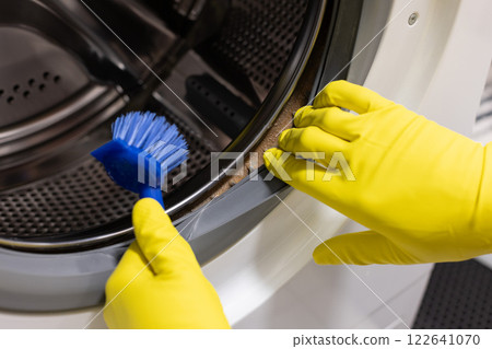 Hands in protective gloves cleaning dirty moldy washing machine. Hands in protective gloves cleaning dirty moldy washing machine. 122641070