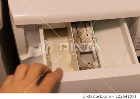 Woman opening container of washing machine with mold, dirt and limescale. Woman opening container of washing machine with mold, dirt and limescale. 122641071