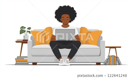 Dominican American man engaged in work on laptop while relaxing on couch surrounded by books 122641248