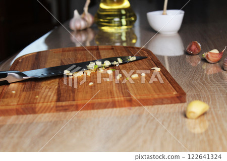 Chopped garlic on a cutting board next to a knife. Making a recipe for garlic butter. Cutting vegetables Chopped garlic on a cutting board next to a knife. Making a recipe for garlic butter. Cutting vegetables 122641324