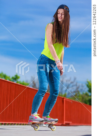 Teen girl skater riding skateboard on street. 122642203