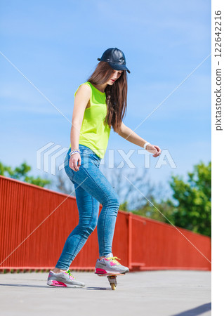 Teen girl skater riding skateboard on street. Teen girl skater riding skateboard on street. 122642216