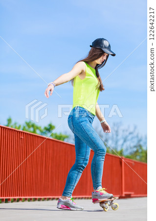 Teen girl skater riding skateboard on street. 122642217