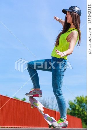 Teen girl skater riding skateboard on street. 122642218