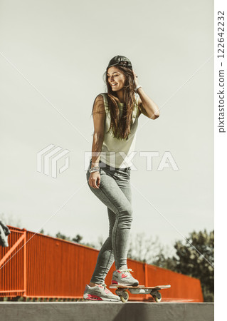 Teen girl skater riding skateboard on street. 122642232