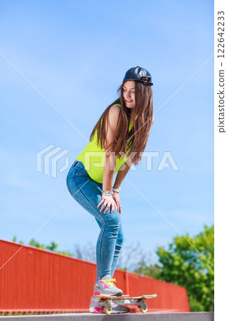 Teen girl skater riding skateboard on street. 122642233