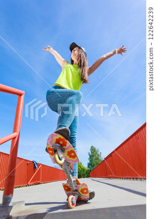 Teen girl skater riding skateboard on street. 122642239