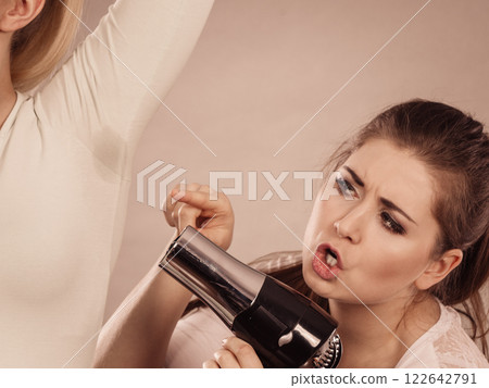 Woman drying friend armpit with hair dryer 122642791