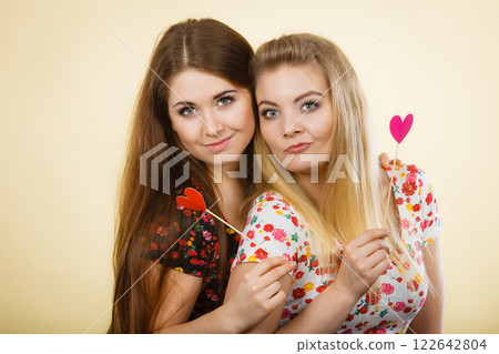 Two happy women holding heart on stick 122642804