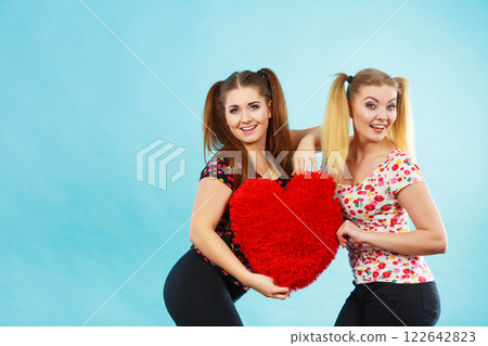 Happy two women holding heart shaped pillow 122642823