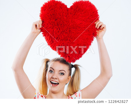 Happy woman holding heart shaped pillow 122642827