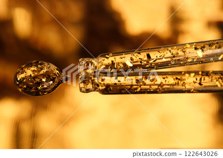 24 k gold facial serum in a pipette on a gold background. 24 k gold facial serum in a pipette on a gold background. 122643026