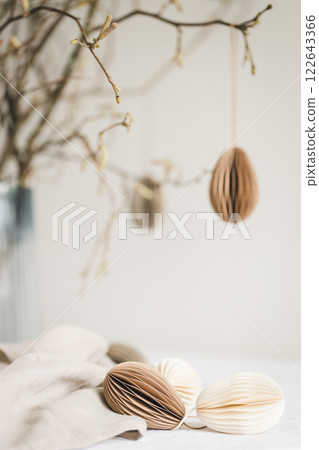 Paper Easter eggs hanging on branches under table with decorations on it. Paper Easter eggs hanging on branches under table with decorations on it. 122643366