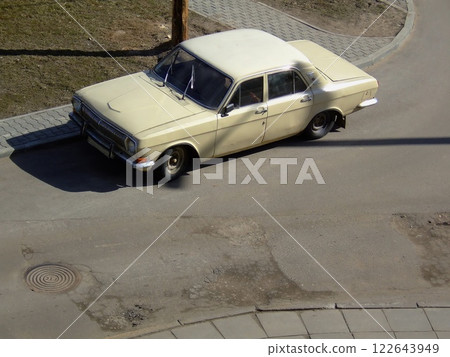 A vintage beige sedan sits parked at the edge of a residential street. The car is slightly angled, showcasing its classic design amidst a clear, sunny atmosphere. A vintage beige sedan sits parked at the edge of a residential street. The car is slightly angled, showcasing its classic design amidst a clear, sunny atmosphere. 122643949