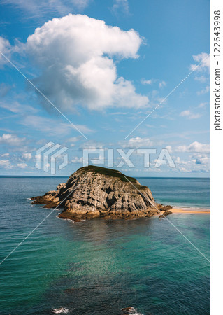 Scenic rocky island with a sandy beach surrounded by ocean Scenic rocky island with a sandy beach surrounded by ocean 122643998