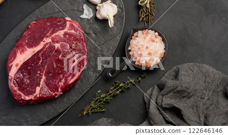 Raw beef steak chuck eye roll on a blck board. Spices for cooking Himalayan salt, peppercorns and thyme sprigs Raw beef steak chuck eye roll on a blck board. Spices for cooking Himalayan salt, peppercorns and thyme sprigs 122646146
