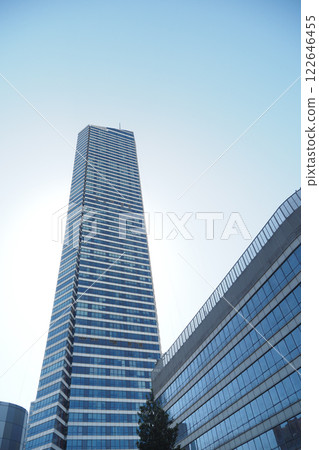 A modern skyscraper rises high against a backdrop of a clear blue sky 122646455