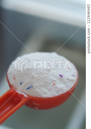 Measuring laundry detergent in a red scoop Measuring laundry detergent in a red scoop 122646465
