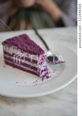 Delicious purple cake served on a white plate with a silver fork at a cozy cafe 122646508