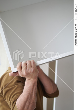 Person lifting a large white board while working on home organization 122646525