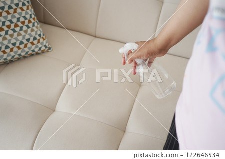 Cleaning a light-colored couch with a spray bottle at home 122646534