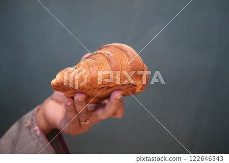 A Hand Gently Holding a Freshly Baked, Golden Brown Croissant 122646543