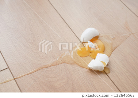 Egg yolk spills onto wooden floor in kitchen accident 122646562
