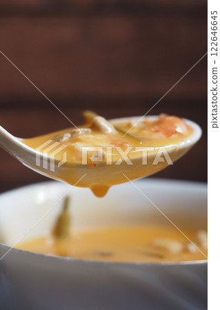 Close-Up of Creamy Soup in a Ladle with a Bowl in Background Close-Up of Creamy Soup in a Ladle with a Bowl in Background 122646645