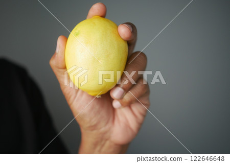 Holding a fresh lemon in a hand Holding a fresh lemon in a hand 122646648