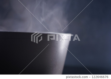 Steam rises from a warm bowl of soup in a dark setting Steam rises from a warm bowl of soup in a dark setting 122646676