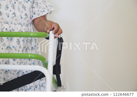 A Child Utilizing a Green Walker Designed for Support and Improved Mobility Skills A Child Utilizing a Green Walker Designed for Support and Improved Mobility Skills 122646677