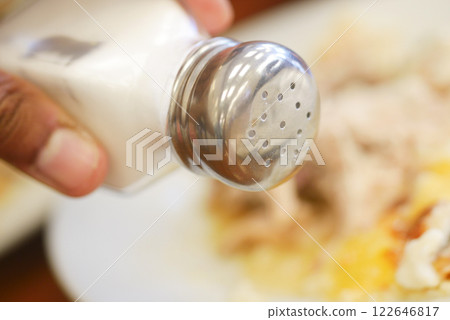 Salt falls from a salt shaker Salt falls from a salt shaker 122646817