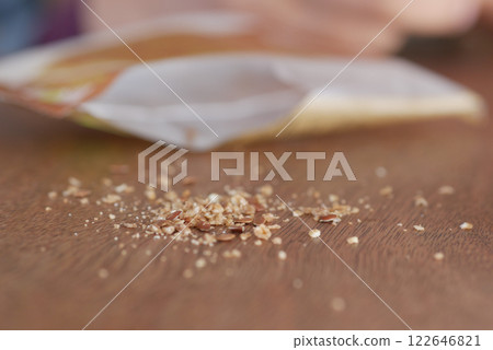 A pile of Crushed Nuts resting on a Wooden Table with a Blurred Background 122646821