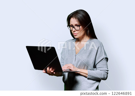 Serious middle aged woman using laptop on white background 122646891