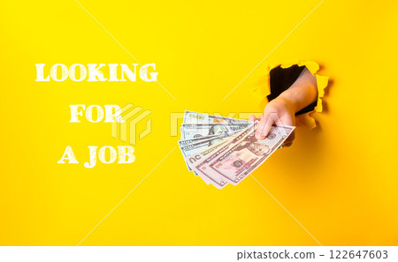 A hand holding a stack of money with the words looking for a job written below 122647603