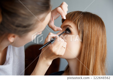 makeup artist glues false eyelashes 122648562
