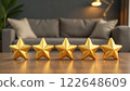 Five golden stars lined up on a wooden surface with a cozy living room setting blurred in the background. Concept of high-quality. 122648609