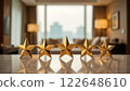 Five golden stars displayed on a marble table in front of a blurred hotel suite. Concept of top tier service.                        122648610